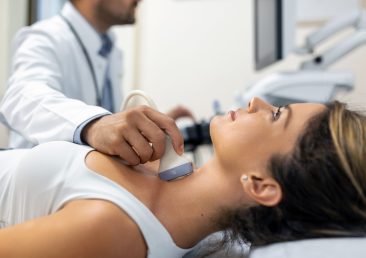 Close up shot of young woman getting her neck examined by doctor using ultrasound scanner at modern clinic