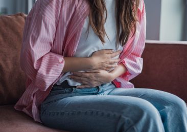Close-up of a teen girl pressing her abdomen, looking distressed due to abdominal pain, flatulence, or digestive issues, experiencing discomfort and gastrointestinal upset at home