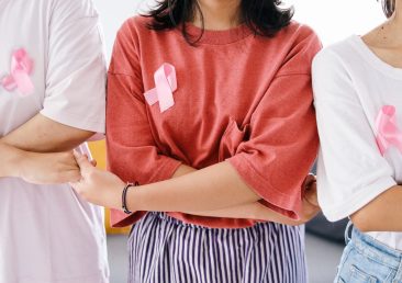mulheres-segurando-as-maos-umas-das-outras-e-usando-fita-rosa-no-peito-conceito-de-apoio-de-solidariedade