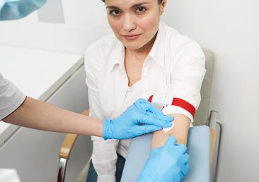 Poor girl. Kind female person sitting near her doctor while going to do blood test