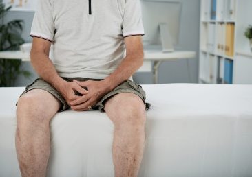 Cropped image of old man sitting on bed in medical office